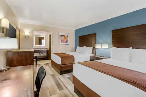 Hotel guest room with two queen beds, blue accent wall, and modern furnishings