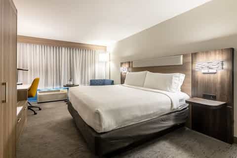 Modern hotel bedroom with king bed, work desk, and contemporary decor