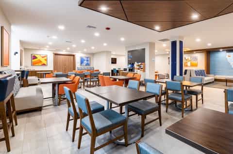 Hotel lobby lounge area with dining tables, chairs, and contemporary interior design