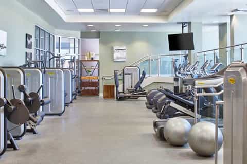 Modern fitness center with cardio machines, exercise bikes, stability balls, and strength training equipment