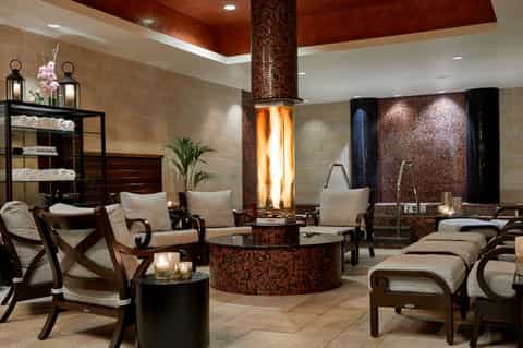 Luxurious spa relaxation area with central fireplace, lounge chairs, and mosaic tile accents