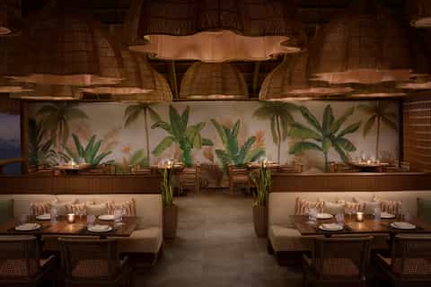 Fine dining restaurant with tropical botanical wall art, wooden seating, and soft ambient lighting