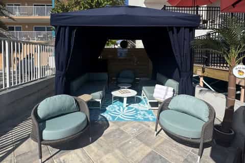 Outdoor cabana with dark navy curtains, mint green seating, and turquoise patterned rug