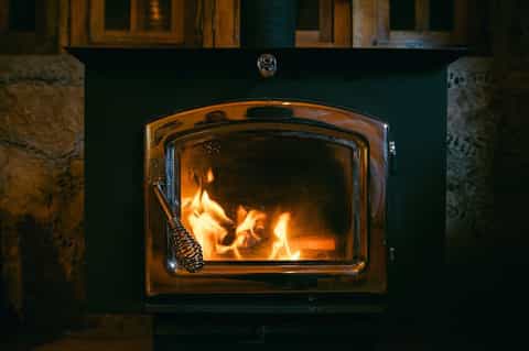 Fireplace with active flames burning inside a dark green surround with wooden mantel