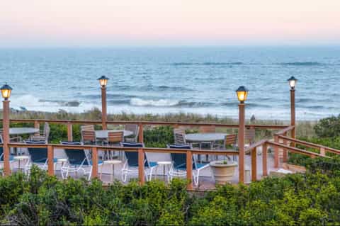 Elevated wooden deck with lounge chairs overlooking beach and ocean at dusk