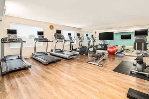 Fitness center with multiple treadmills, stationary bikes, exercise equipment, and large windows