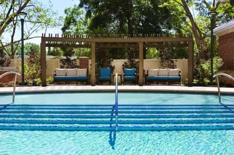 Residential pool with lane markings and covered lounge seating area beneath pergola
