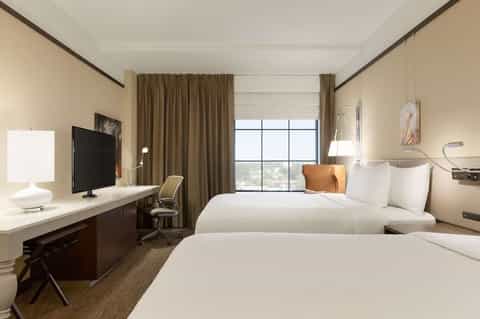 Modern hotel guest room with two queen beds, desk, and panoramic window views