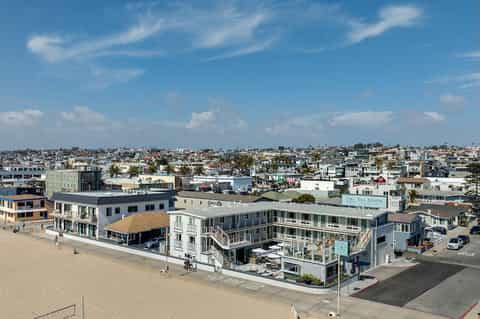 Aerial view of beachfront resort complex with multiple buildings, beach access, and surrounding neighborhood
