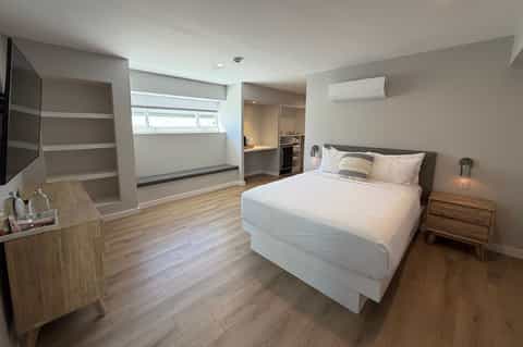 Spacious master bedroom with queen bed, wooden nightstands, and sitting area with shelving