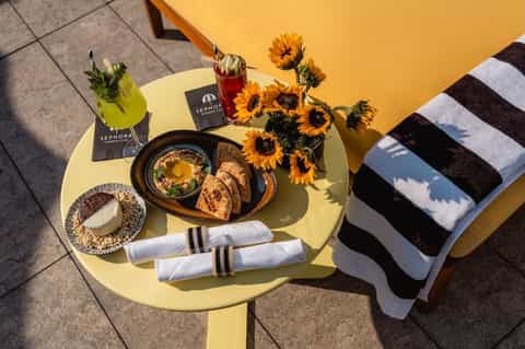 Yellow bistro table with sunflowers, cocktails, appetizers, and striped towel at Sephora venue