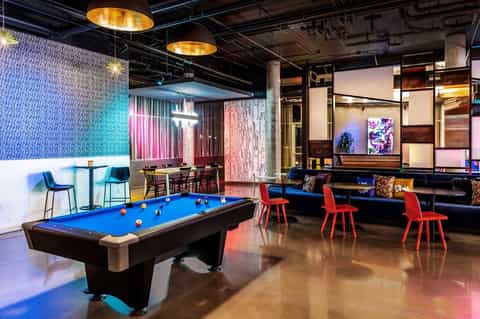 Game room with blue pool table, neon lighting, pink accent walls, and modern furniture