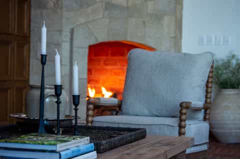 Cozy fireplace lounge with gray upholstered chair, candles, and valley views through windows