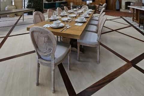 Formal dining room with long wooden table, upholstered chairs, and geometric wood flooring