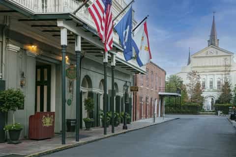 Historic colonial-style storefront with green awning, flags, and white church steeple in background