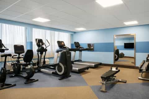 Modern fitness center with cardio equipment, mirrors, and blue accent walls