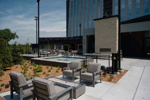 Rooftop pool and fire pit lounge with modern hotel building, landscaping, and evening ambiance