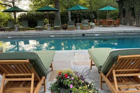 Resort poolside with lounge chairs, green umbrellas, and flowering landscaping