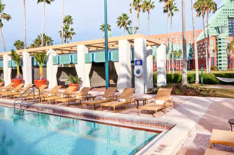 Modern poolside cabanas with white columns and tan lounge chairs beside bright turquoise pool