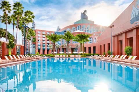 Resort courtyard pool surrounded by coral-pink buildings and palm trees