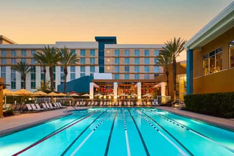 Olympic-length lap pool with lane dividers at dusk, hotel buildings and palm trees in background