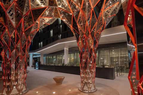 Modern building entrance at night with red geometric metal archways and glass doors