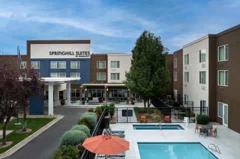 Aerial view of Springhill Suites hotel complex with two pools, orange umbrellas, and surrounding buildings