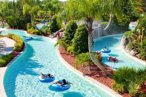 Lazy river with turquoise water winding through lush tropical landscaping and palm trees