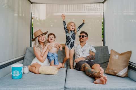 Family of four relaxing on gray couch in modern screened outdoor living space