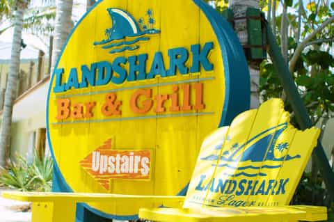 Yellow Landshark Bar & Grill sign with palm trees in tropical setting