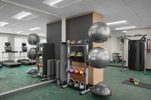 Fully equipped fitness center with exercise equipment, weights, stability balls, and mirrored walls
