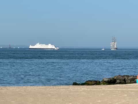 Ocean beach view with cruise ship and tall ship sailboat on horizon