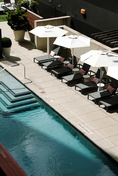 Resort poolside with loungers under white umbrellas and black wall