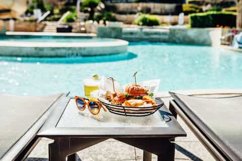 Poolside lunch with burgers and drinks beside turquoise resort pool with curved edges