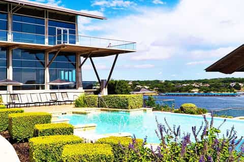 Modern poolside bar and lounge area overlooking waterfront with contemporary architecture