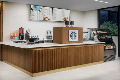 Modern Starbucks-branded coffee counter with wood paneling, menu boards, and espresso machines
