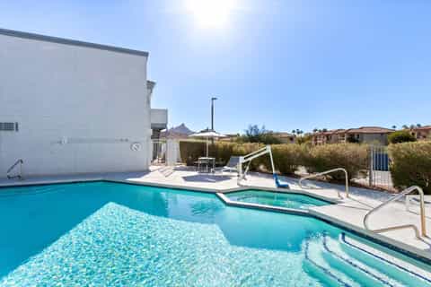 Outdoor pool and hot tub with desert landscape and mountain views under clear sky