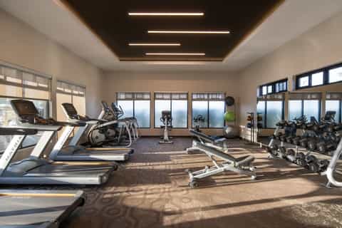 Modern hotel fitness center with treadmills, dumbbells, and large windows with mountain views