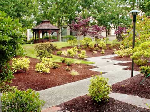 Manicured gardens with winding paths, gazebo, flowering trees, and landscaped grounds