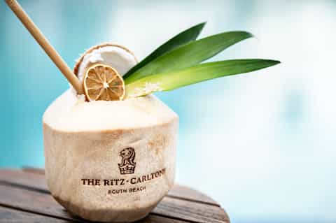 Tropical coconut drink with straw garnished with dried lemon slice and green leaves at The Ritz-Carlton South Beach