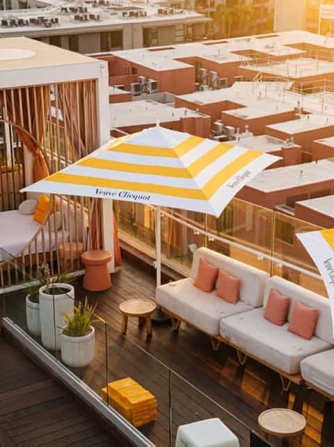 Aerial view of resort deck with Veuve Clicquot branded striped umbrella and white lounge seating