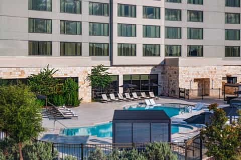 Resort pool with spa area, lounge chairs, metal storage box, and modern hotel architecture