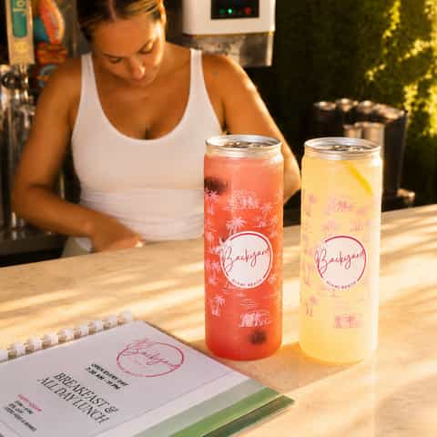 Backyard Cafe bartender preparing colorful cocktails at an indoor bar with tropical branding
