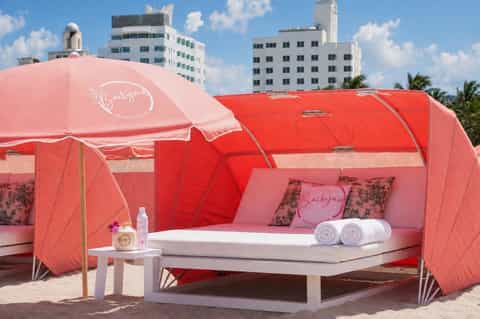 Pink and red glamping pod with bedding and amenities on Miami beach with city skyline