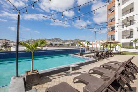 Rooftop pool with turquoise water, lounge chairs, string lights, and mountain views at a modern hotel resort