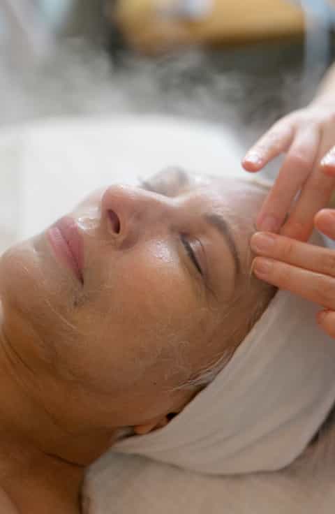 Esthetician applying facial treatment to client's face during spa service