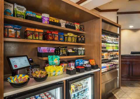 Hotel convenience store with snack shelves, refrigerated beverages, point-of-sale system, and display cases