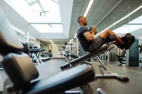 Man doing weighted abdominal exercises on machine in bright, modern gym