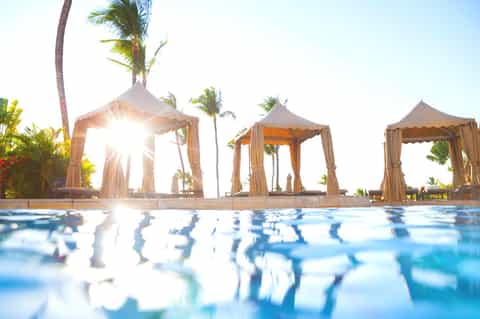 Luxury resort pool with elegant cabanas and palm trees at golden hour