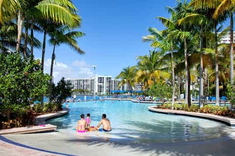 Family-friendly lazy river with palm trees, shallow water entry, and resort buildings